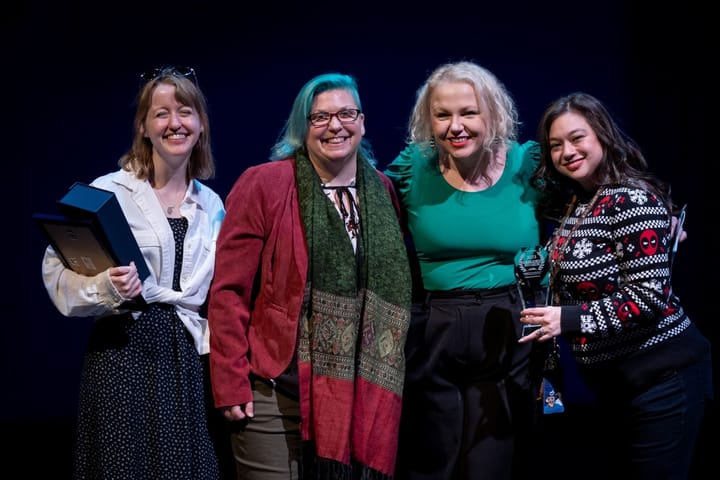 Four women stand together for a picture smiling.