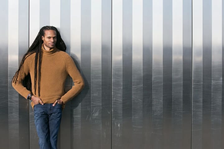 In front of a silver wall, Stacy D. Flood stands looking at the camera.